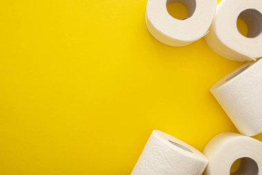 Sarı arkaplandaki temiz tuvalet kağıdı rulolarının üst görünümü