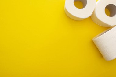 Sarı arkaplandaki temiz tuvalet kağıdı rulolarının üst görünümü