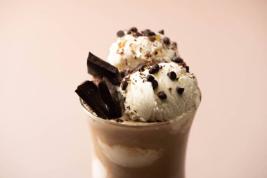 Bir bardak dondurmalı milkshake, bir parça çikolata ve bej üzerine şekerleme. 