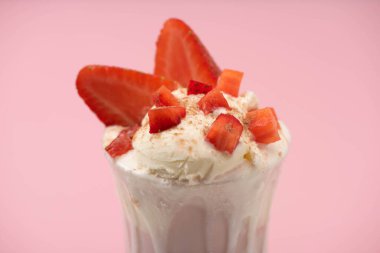 Selective focus of glass of milkshake with ice cream and strawberries isolated on pink clipart