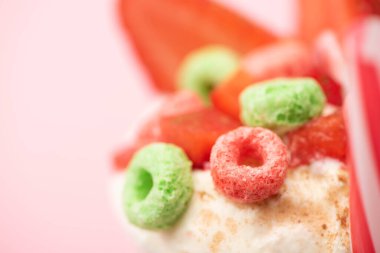 Çilekli milkshake 'in seçici odak noktası. Dondurma ve pembe arka planda renkli şekerler.