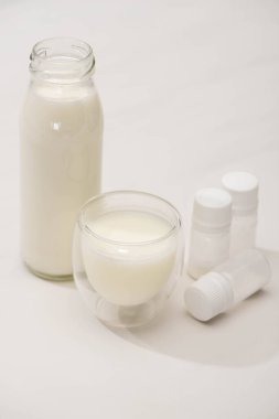 High angle view of bottle and glass of homemade yogurt near containers with starter cultures on white clipart