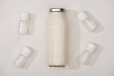 Top view of bottle of homemade yogurt and containers with starter cultures on white background clipart