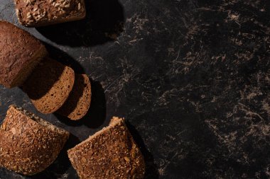 Kesilen tahıllı ekmeğin siyah yüzeydeki üst görüntüsü