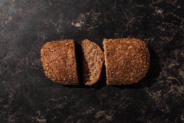 Kesilen tahıllı ekmeğin siyah yüzeydeki üst görüntüsü