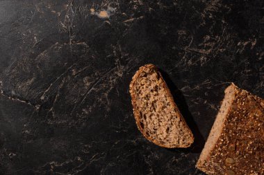 Kesilen tahıllı ekmeğin siyah yüzeydeki üst görüntüsü