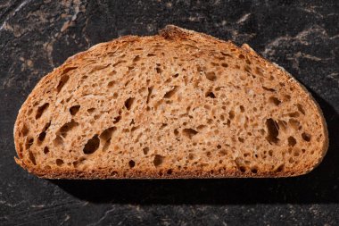 Kaya gibi siyah yüzeyde kahverengi ekmek diliminin üst görüntüsü