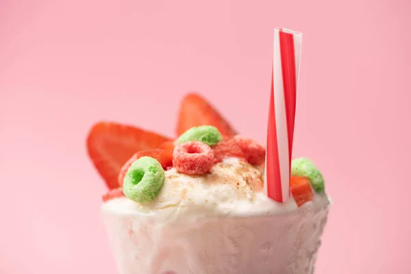 ピンクの背景にアイスクリーム イチゴの半分 キャンディーや飲み物わらとミルクシェイクのガラスの選択的な焦点 — ストック写真