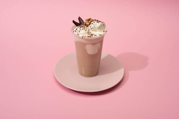High angle view of disposable cup of chocolate milkshake on plate on pink background