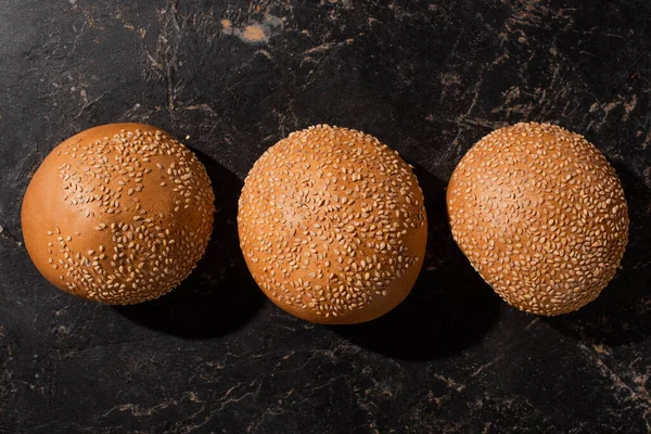 Draufsicht Auf Frisch Gebackene Sesambrötchen Auf Steinschwarzer Oberfläche — Stockfoto