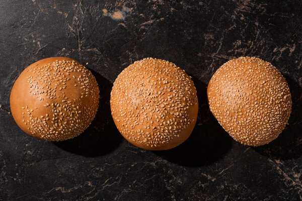 top view of fresh baked sesame buns on stone black surface