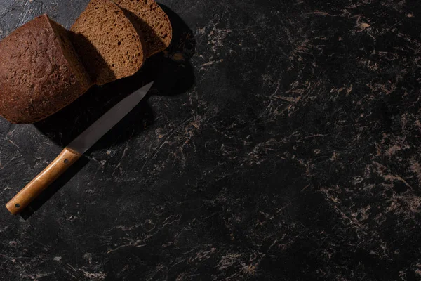Kaya Gibi Siyah Yüzeyde Bıçaklı Taze Kesilmiş Kahverengi Ekmeğin Üst — Stok fotoğraf