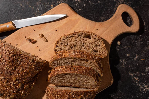 Cut Whole Grain Bread Cutting Board Knife Stone Black Surface — Stock Photo, Image