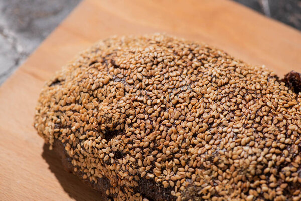 fresh baked black bread with sesame on cutting board