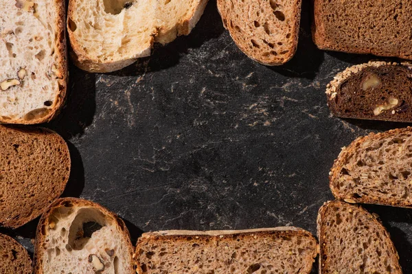 Bovenaanzicht Van Vers Gebakken Brood Plakjes Stenen Zwarte Ondergrond — Stockfoto