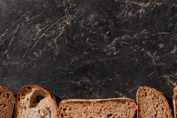 石黑表面新鲜烘焙面包片的顶部视图 — 图库照片