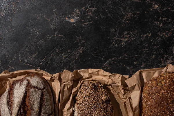 黑色石面纸上新鲜烘烤全麦面包面包的顶部视图 — 图库照片