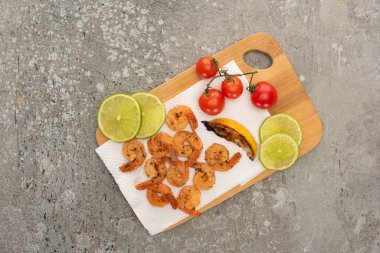 top view of fried shrimps with cherry tomatoes and lime on grey concrete background clipart