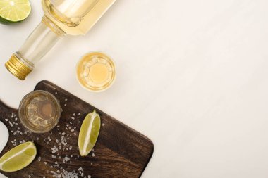 Limonlu altın tekila manzarası, beyaz mermer yüzeyde ahşap kesim tahtası.