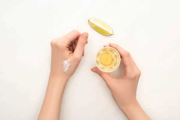 白い背景にライムと塩で金色のテキーラを飲む女性のクロップドビュー — ストック写真