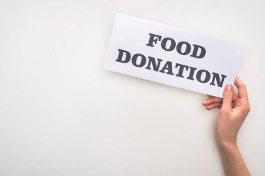 cropped view of woman holding card with food donation lettering on white background clipart