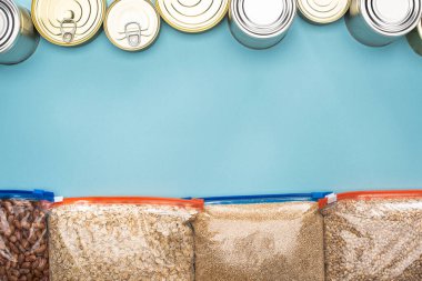 top view of cans and groats in zipper bags on blue background with copy space clipart