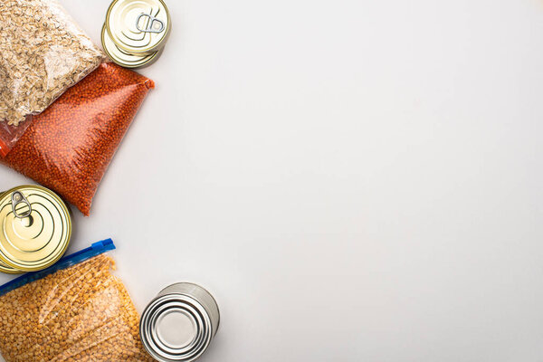 top view of cans and groats in zipper bags on white background, food donation concept