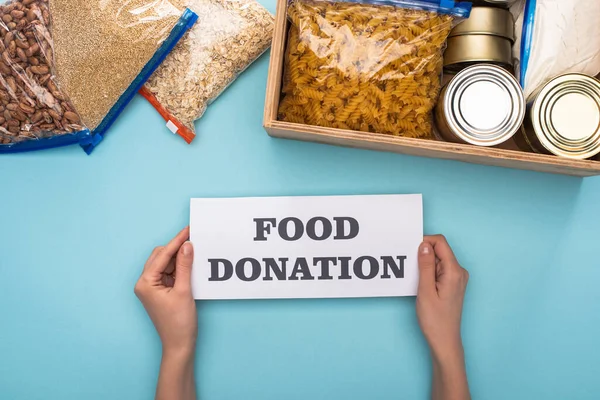 Cropped View Woman Holding Card Food Donation Lettering Cans Groats — Stock Photo, Image