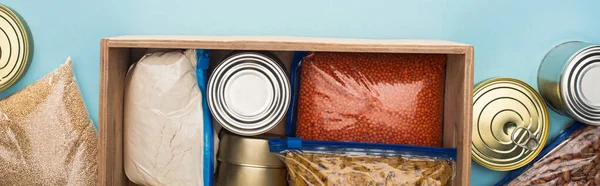 蓝色背景木箱拉链袋中罐和槽的顶部视图 食物捐赠概念 — 图库照片