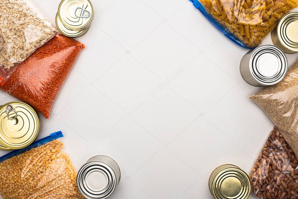 top view of cans and groats in zipper bags on white background, food donation concept