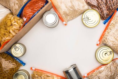 top view of cans and groats in zipper bags with wooden box on white background, food donation concept clipart