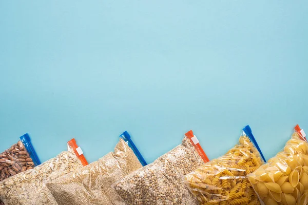 青い背景のジッパー袋の中のパスタ豆と穀物のトップビュー 食糧寄付の概念 — ストック写真