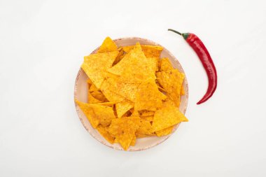 top view of corn nachos with red chili pepper on white background