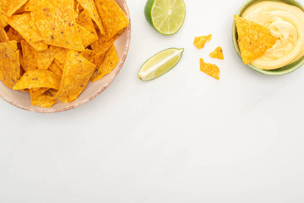 вид на кукурузные начос с соусом из лайма и сыра на белом фоне
