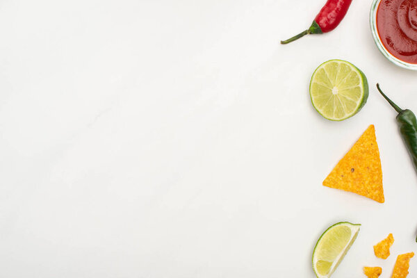 top view of corn nachos with lime, chili peppers, ketchup on white background