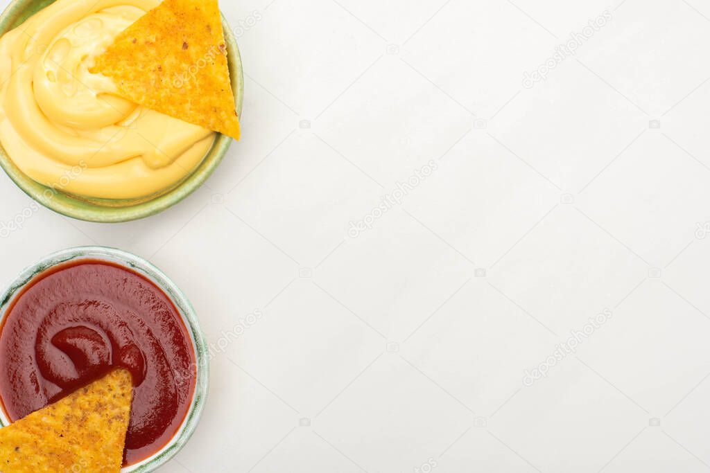 top view of corn nachos with cheese sauce and ketchup on white background
