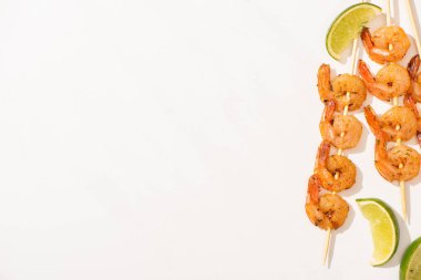 top view of prawns on skewers with lime on white background clipart
