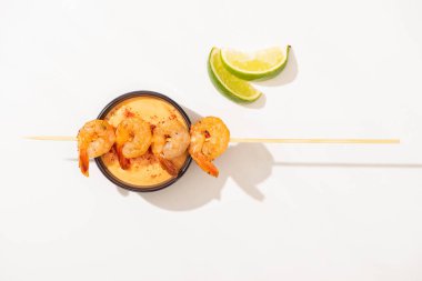 top view of delicious fried prawns on skewer with lime and sauce on white background clipart