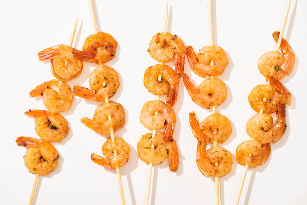 top view of delicious fried prawns on skewers on white background