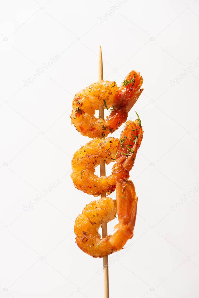 close up view of tasty fried prawns on skewer on white background