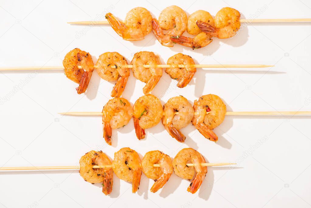 top view of prawns on skewers on white background