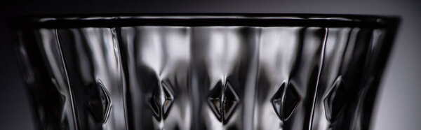 close up view of empty faceted shot glass on dark background, panoramic shot