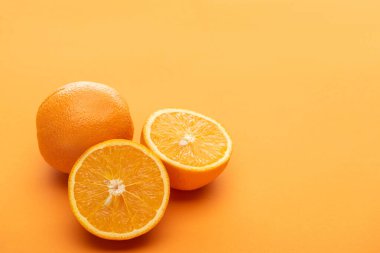 ripe delicious cut and whole oranges on colorful background clipart