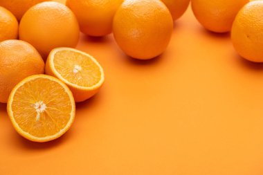 ripe delicious cut and whole oranges on colorful background clipart