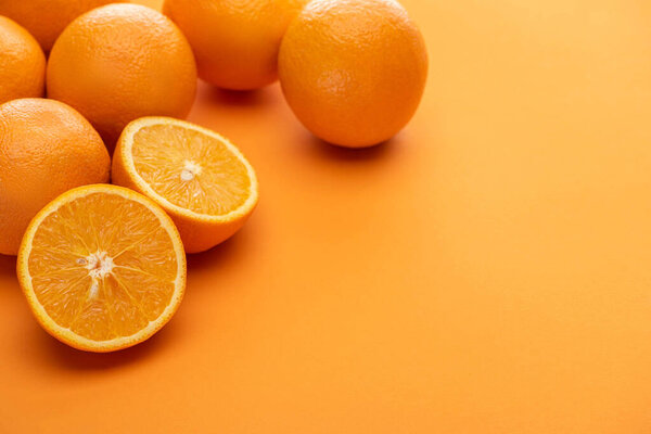 спелый вкусный покрой и целые апельсины на красочном фоне
