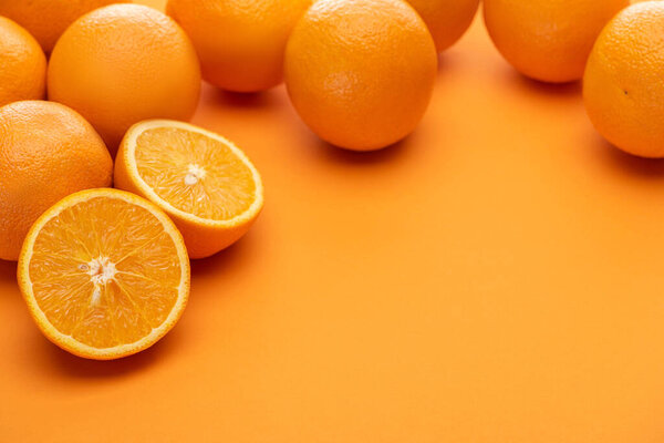 ripe delicious cut and whole oranges on colorful background