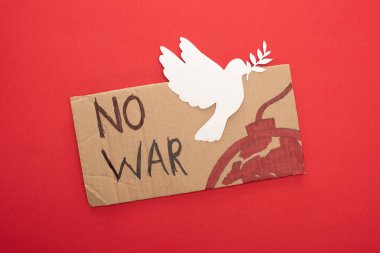 Savaş harfi olmayan mukavva levhanın üst görüntüsü ve kırmızı arka planda beyaz güvercin olan bomba.
