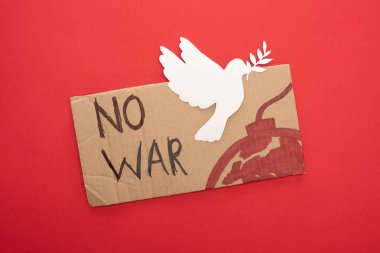 top view of cardboard placard with no war lettering and bomb with white paper dove on red background clipart