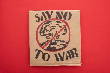 top view of cardboard placard with say no war to war lettering and explosion in stop sign on red background clipart