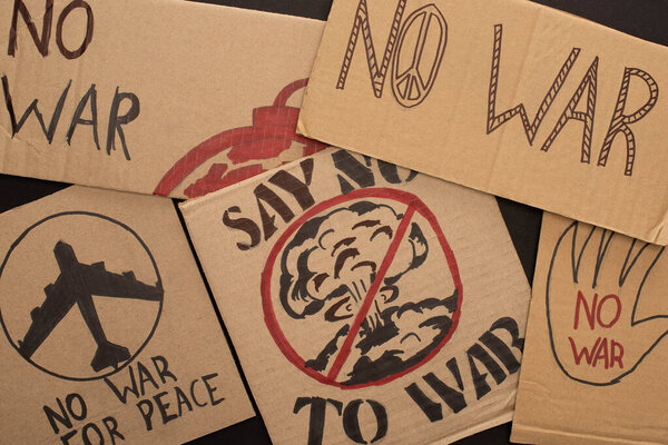 top view of cardboard placards with no war lettering and drawings on black background